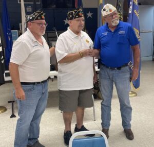 Department Commander Michael Gambler Raymond and Ppst Commander Larry Roberts presenting membership chairman Steve Pasztor with a challenge coin and pin